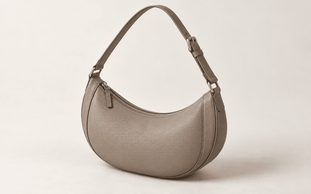 Illustration of a taupe crescent bag with a curved body and adjustable shoulder strap